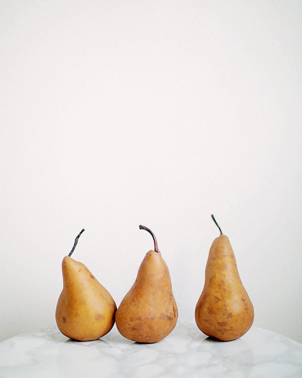 three brown fruits on white textile